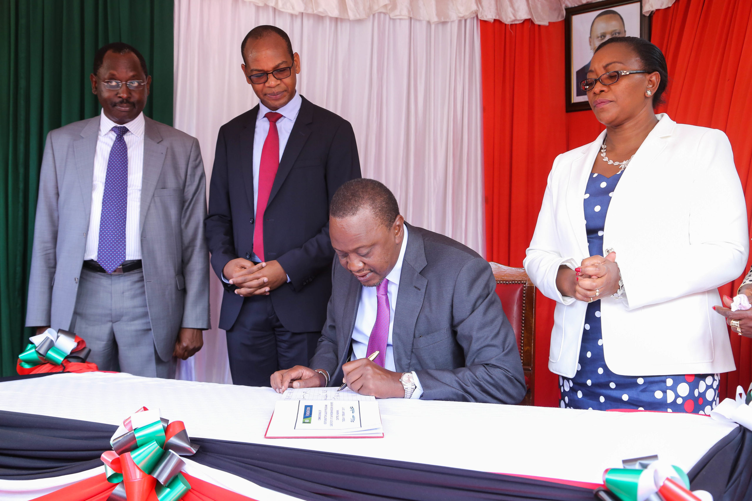 President Uhuru Kenyatta signs the Guest book on arrival at the venue during the commissioning of the 2jiajri class of 2017. Looking on is (L-R) KCB Chairman Ng'eny Biwott, KCB Group MD and CEO Joshua Oigara and Youth and Gender Affairs CS Sicily Kariuki.