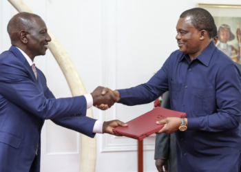 President William Ruto (L) exchanging a document with Attorney General Justin Muturi